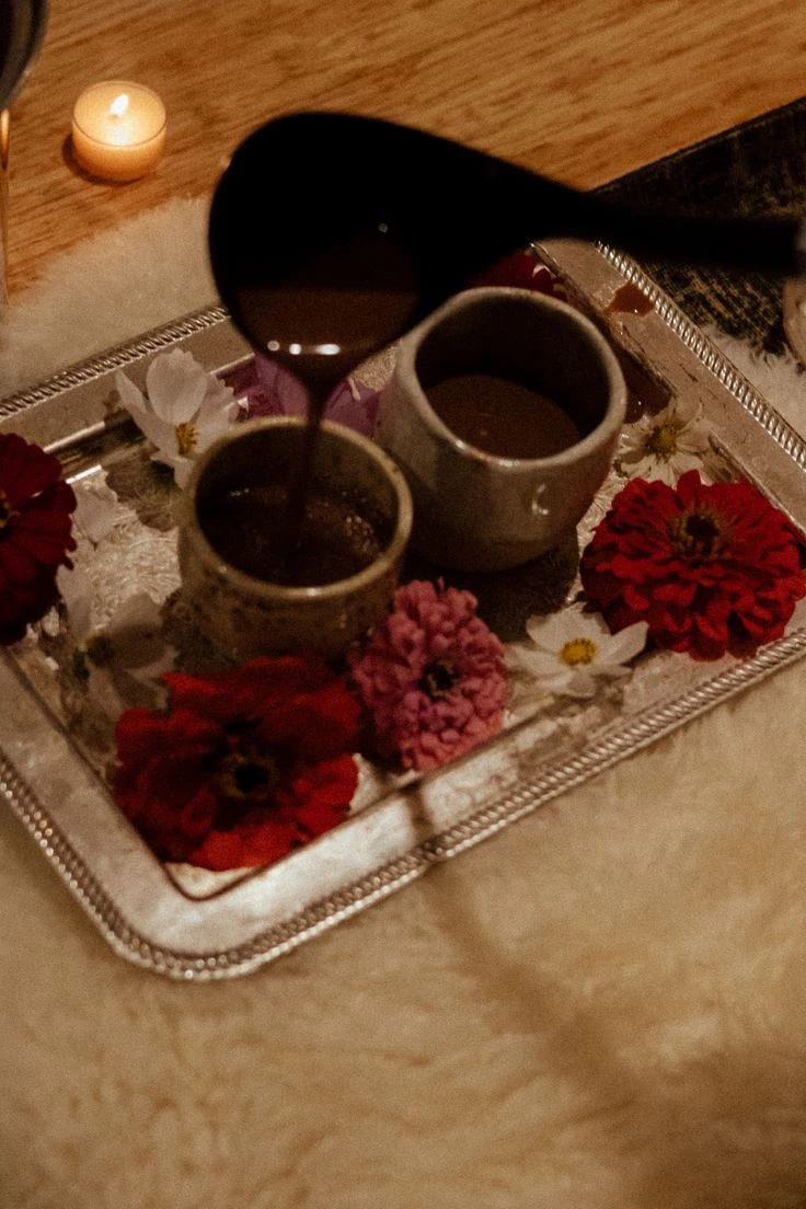Ceremonial cacao poured into a cup on a flower-lined tray